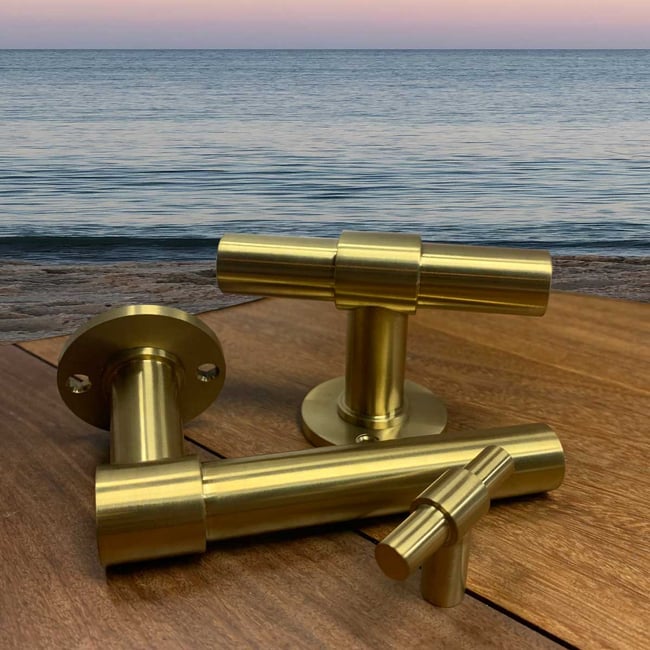 FORMANI's satin gold PVD finished door handle near a coastal environment